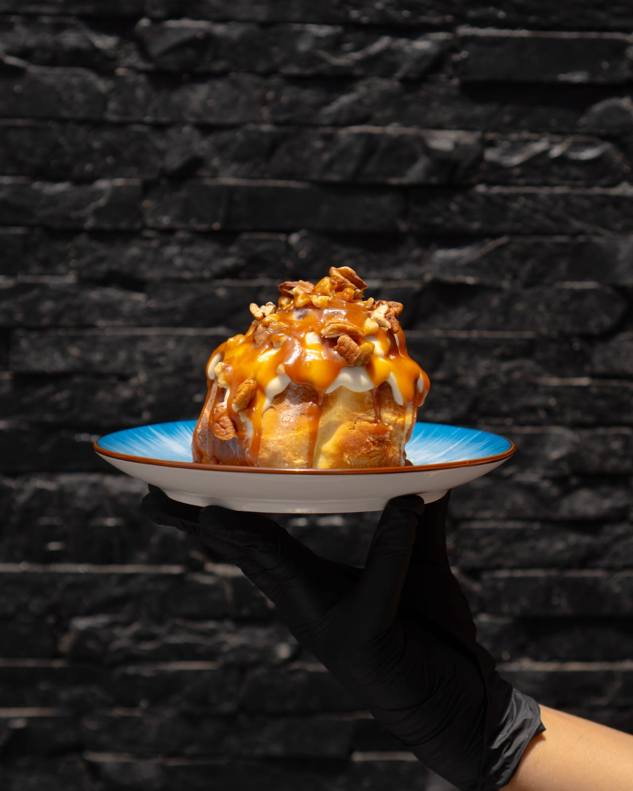 Roulé à la cannelle caramel et noix de pécan servi sur assiette turquoise